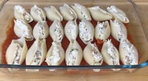 Stuffed pasta shells in tomato sauce, ready to bake in a glass dish. Perfect for an Italian dinner or meal prep.